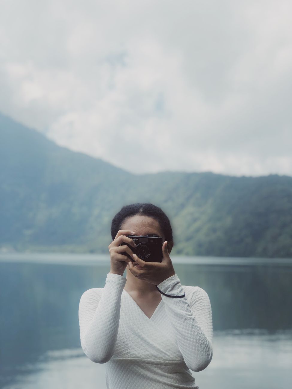 Woman taking a photo by Lake Batur with misty mountain views in Bali