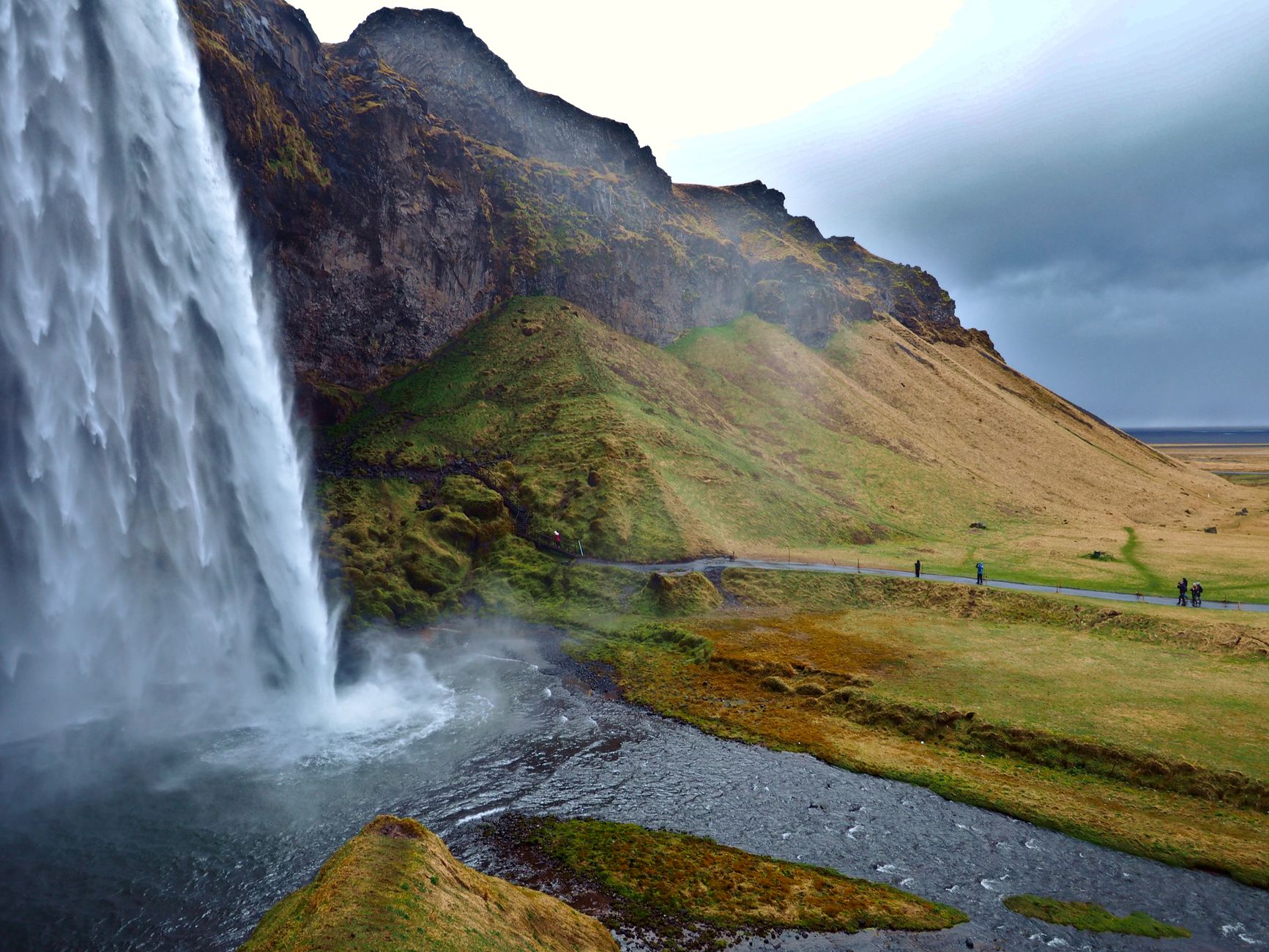 Waterfall and green mountains on a road trip through Iceland