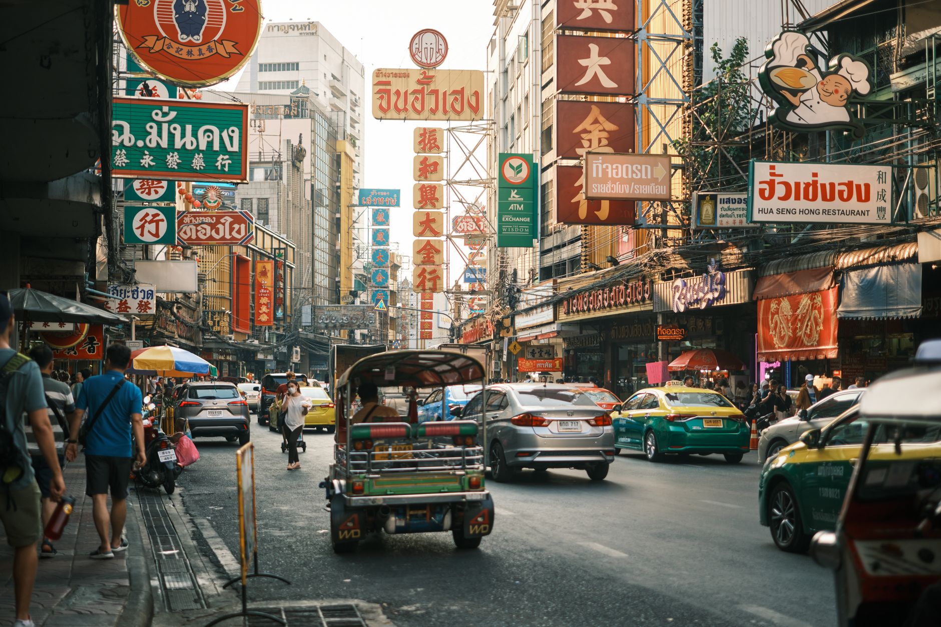 Busy street in Bangkok Chinatown with tuk-tuks, signs, and traffic in Thailand