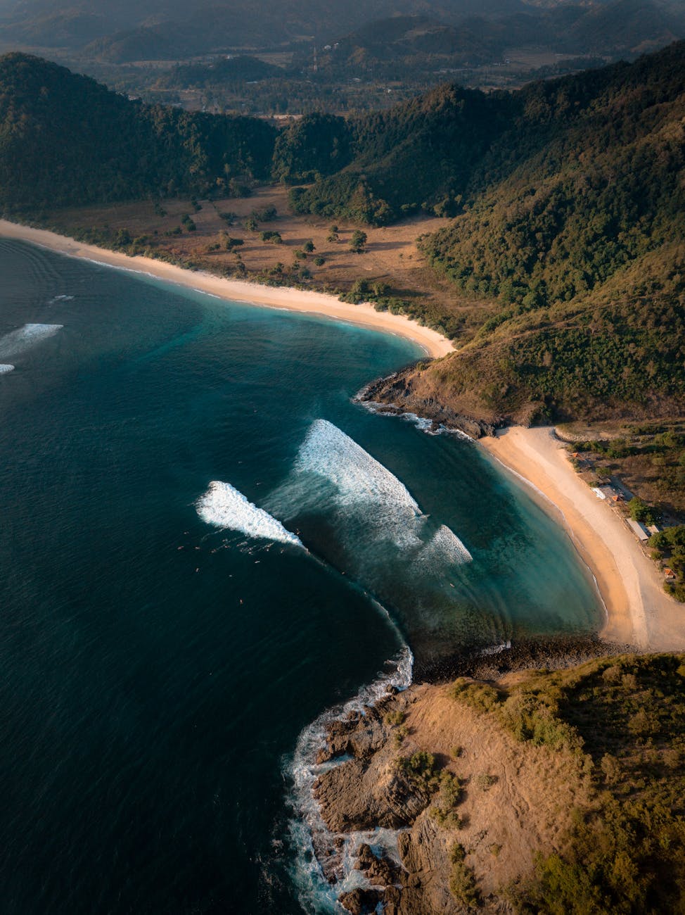 Aerial view of Lombok beach with turquoise water, green hills, and white sand coastline