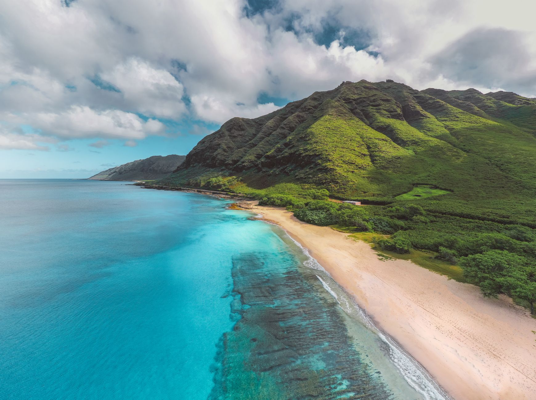 Aerial view of green mountains and turquoise coastline in Hawaii