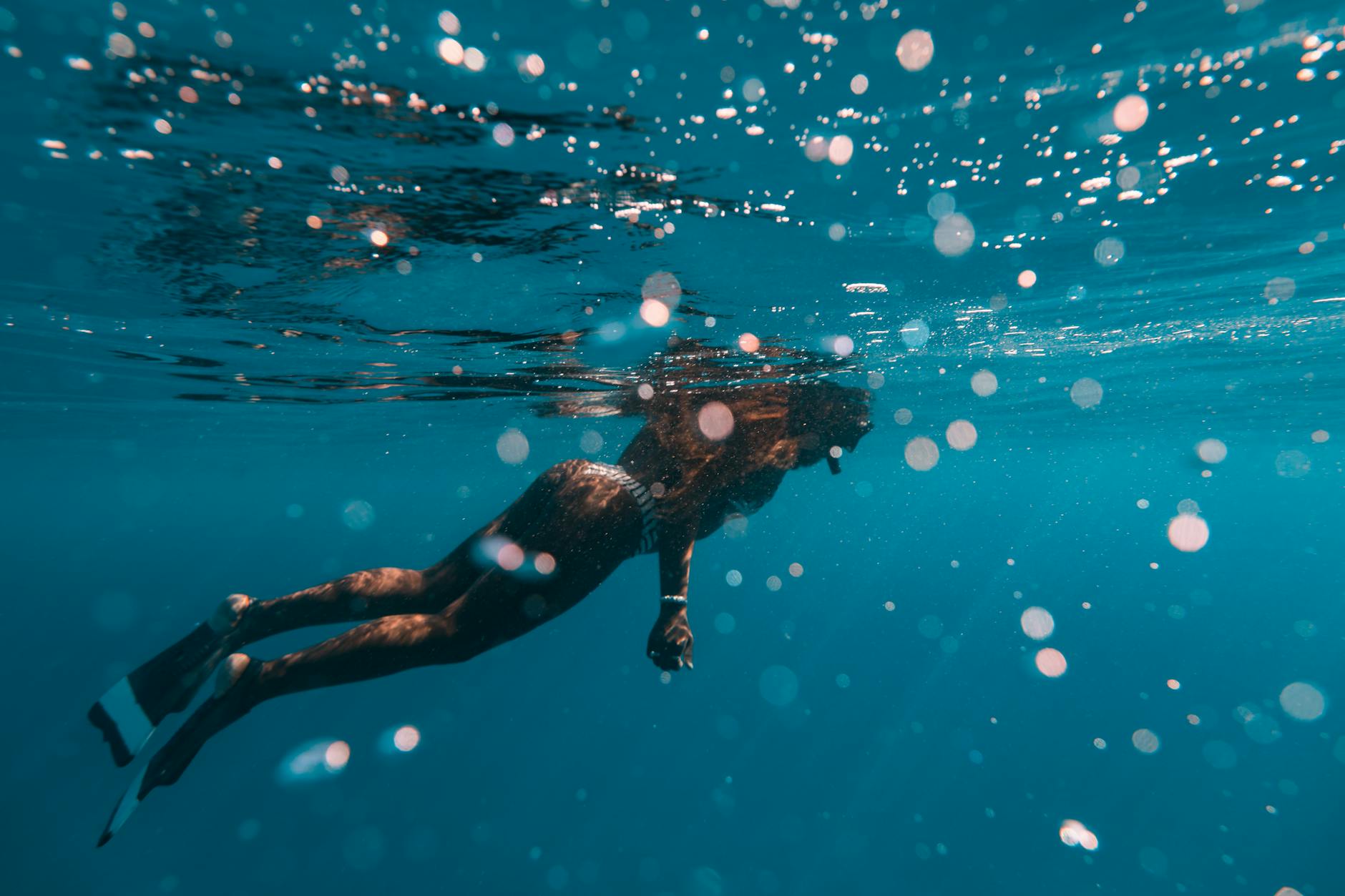 Woman snorkeling underwater in clear blue water near Menjangan, Bali