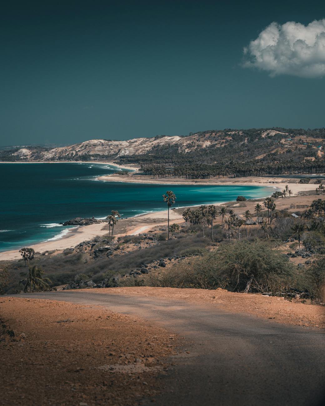 Aerial view of the Sumba coastline with white sand beaches, blue ocean, and dry rolling hills