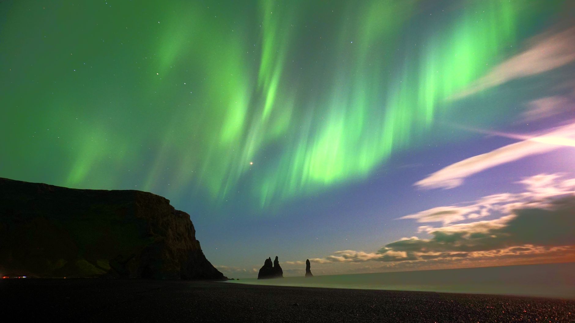 Northern lights glowing over the black sand beach in Iceland