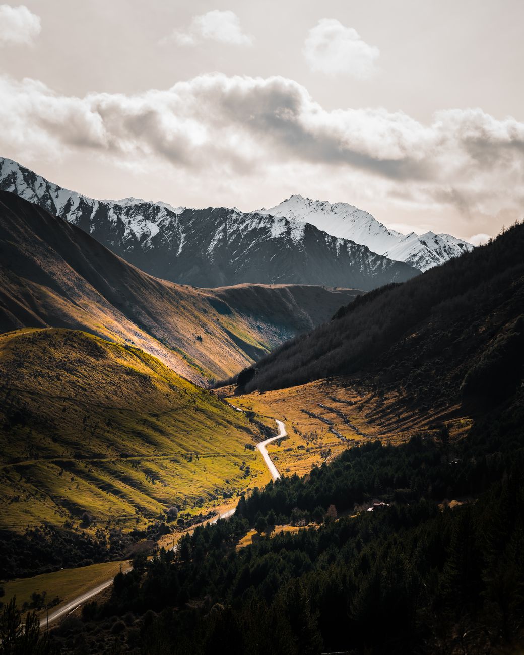 Winding road through a mountain valley with snowy peaks in New Zealand