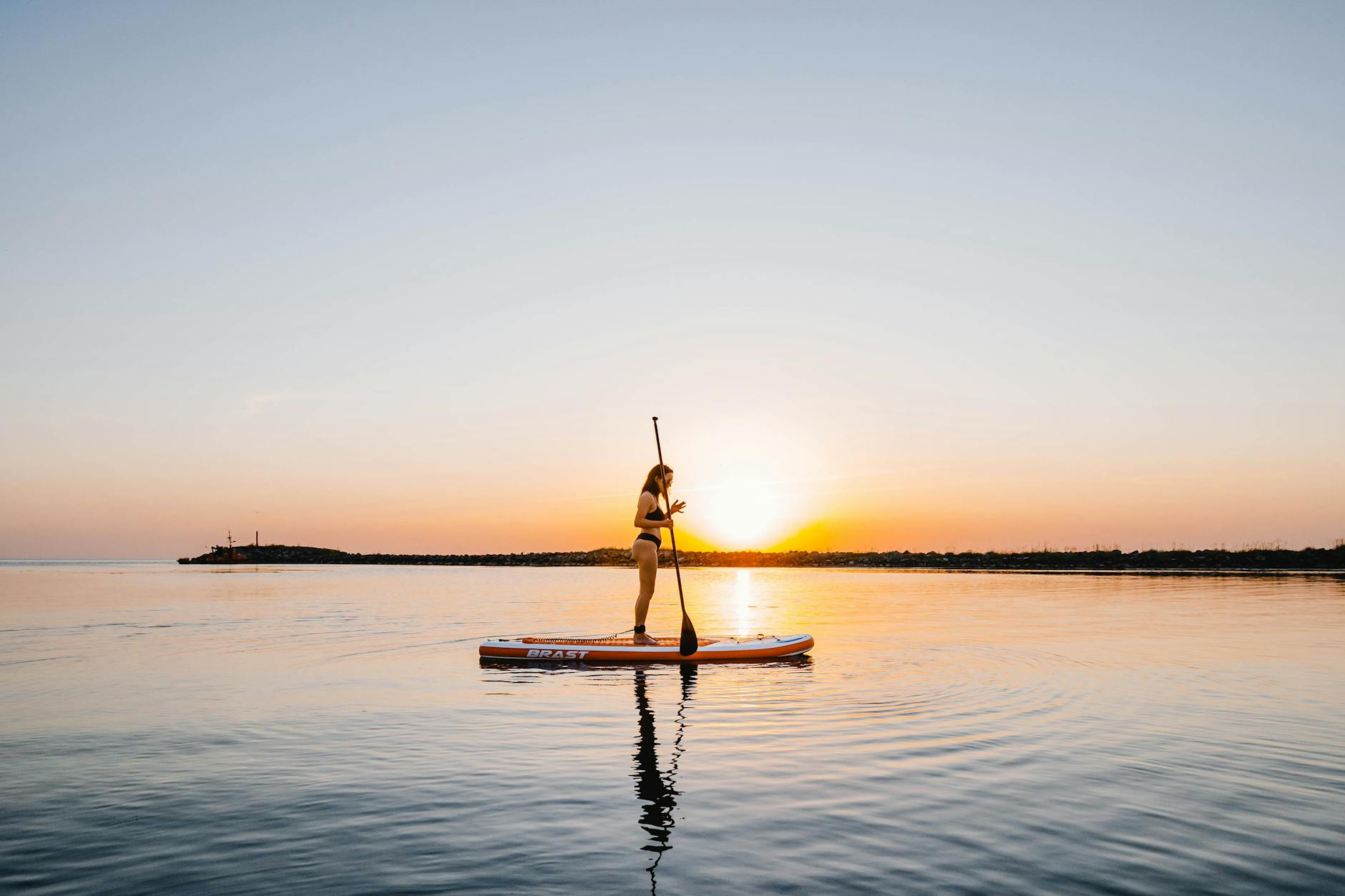Person paddleboarding at sunset on the calm water in Sanur, Bali