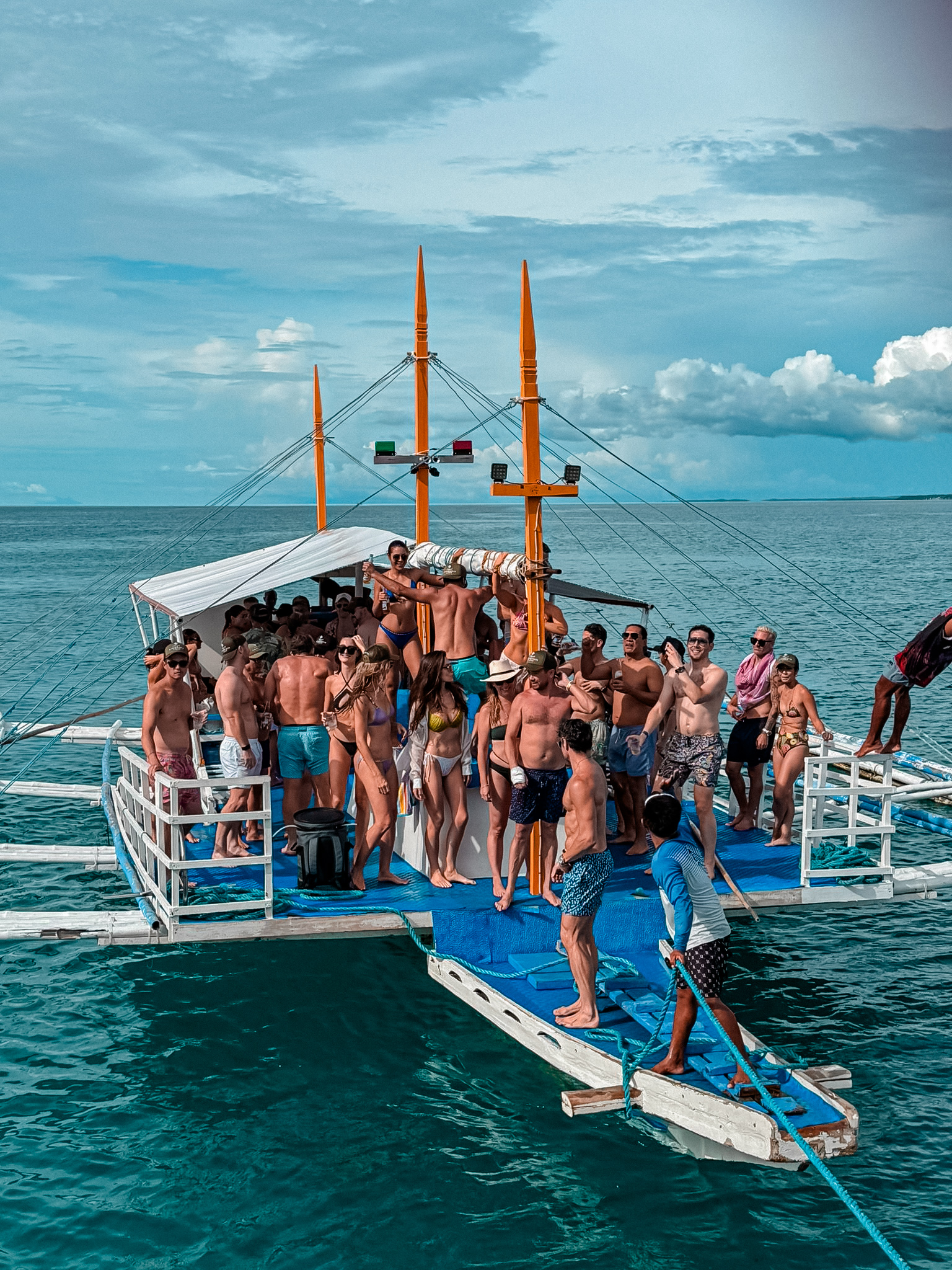 Island-hopping boat with travelers in clear blue water in the Philippines