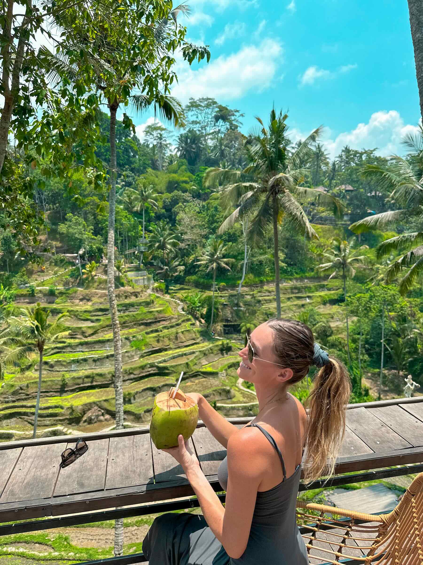 Girl sitting with a coconut in hand, on a sunny day in the Tegalalang ricefields in Ubud, Bali.