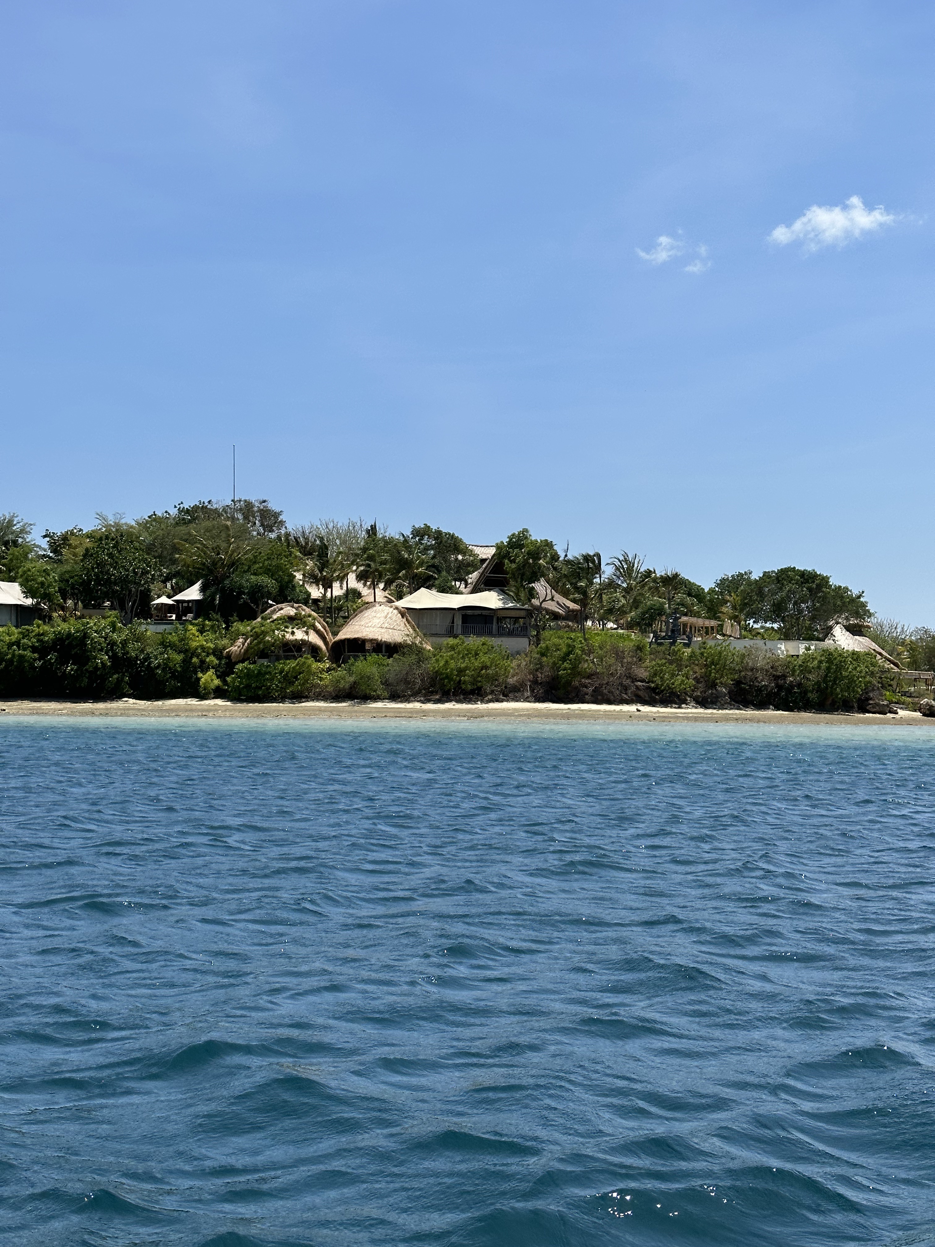 Menjangan Island beach: View of the coastline and blue ocean from a boat approaching Menjangan Island in West Bali