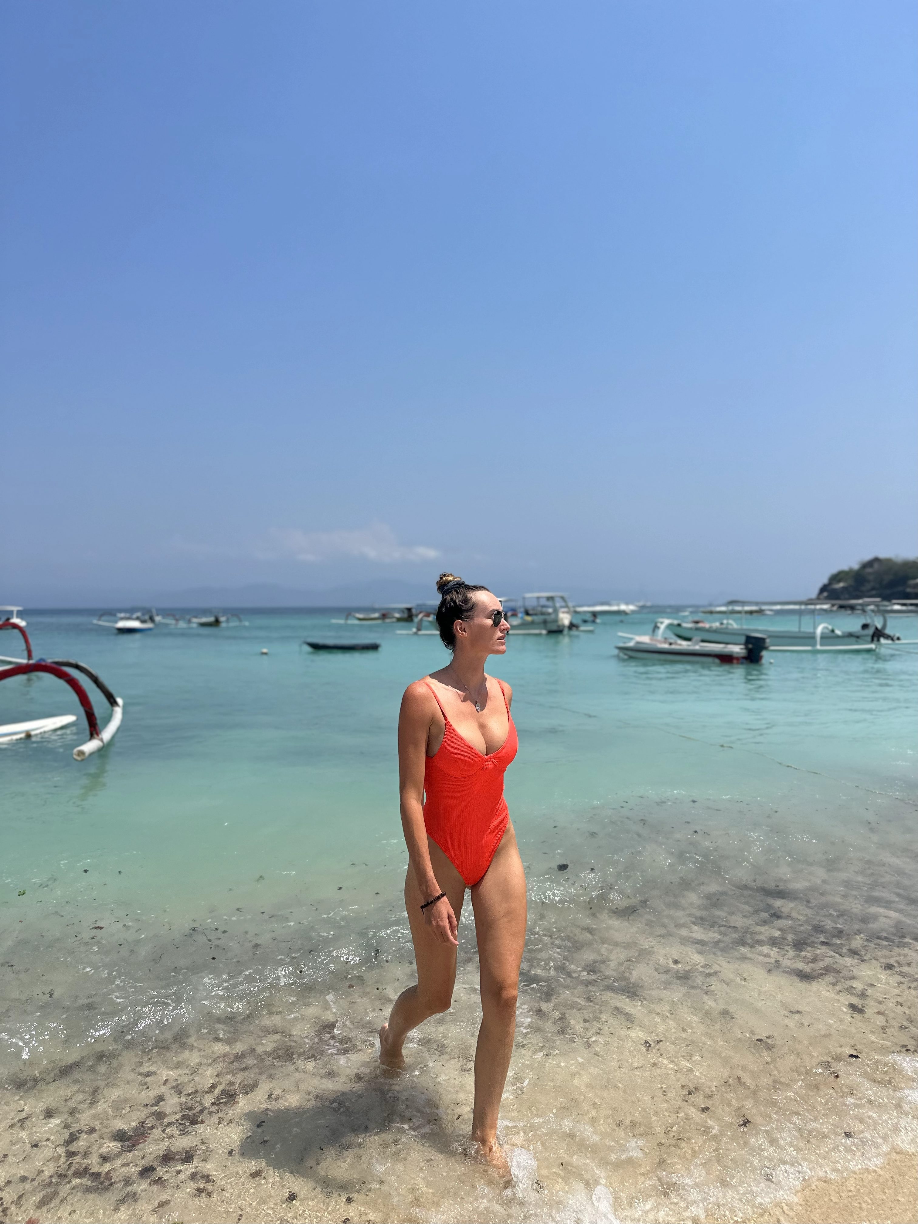 Woman walking in clear shallow water on a beach in Nusa Lembongan, Bali