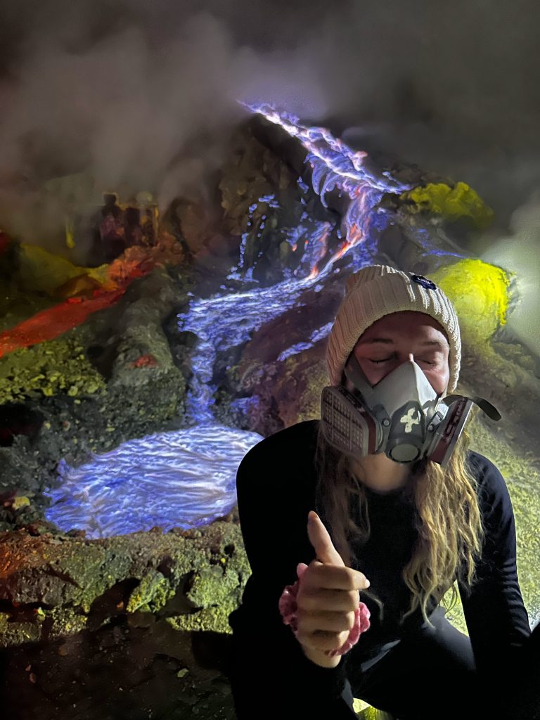 Traveler wearing a gas mask near the blue fire at Kawah Ijen volcano
