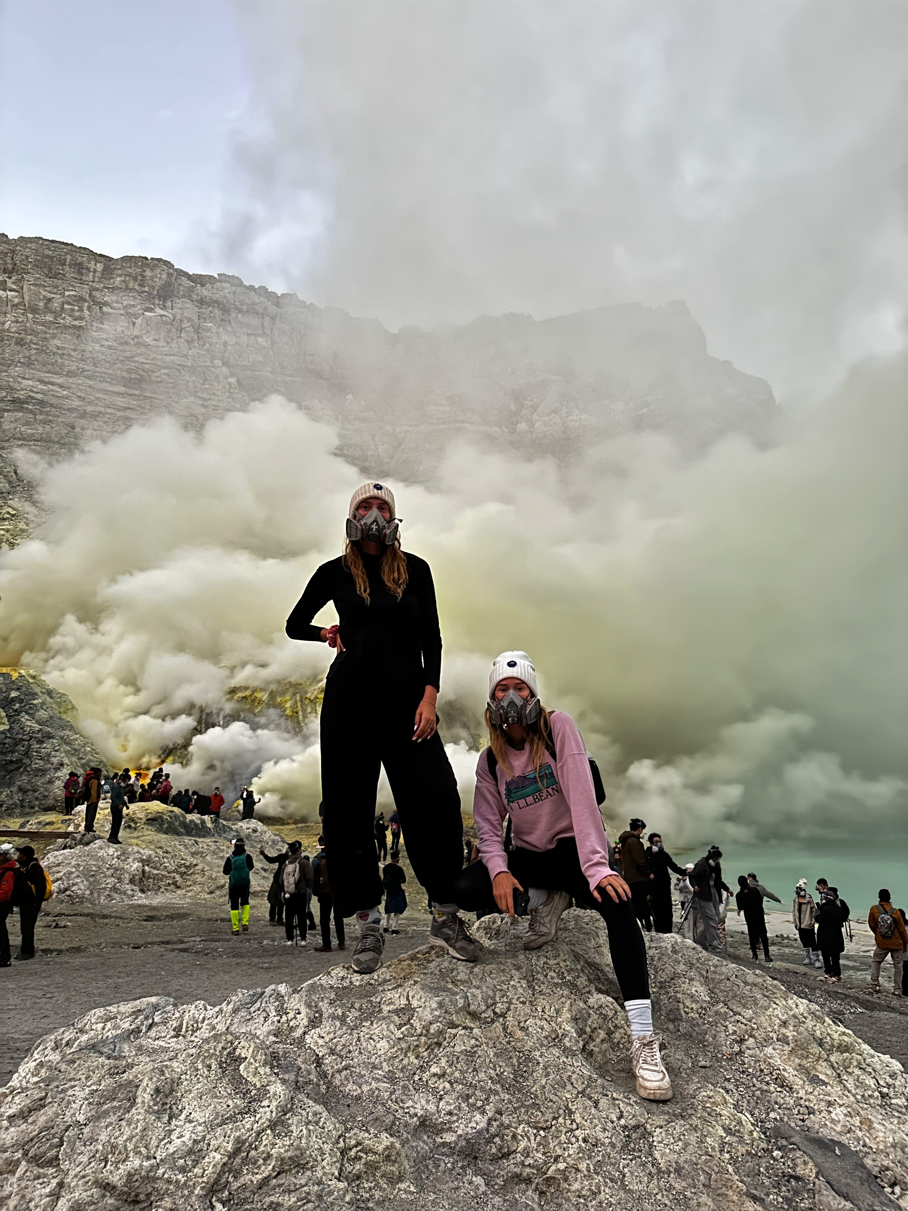 Travelers standing near thick sulfur fumes at Kawah Ijen crater lake
