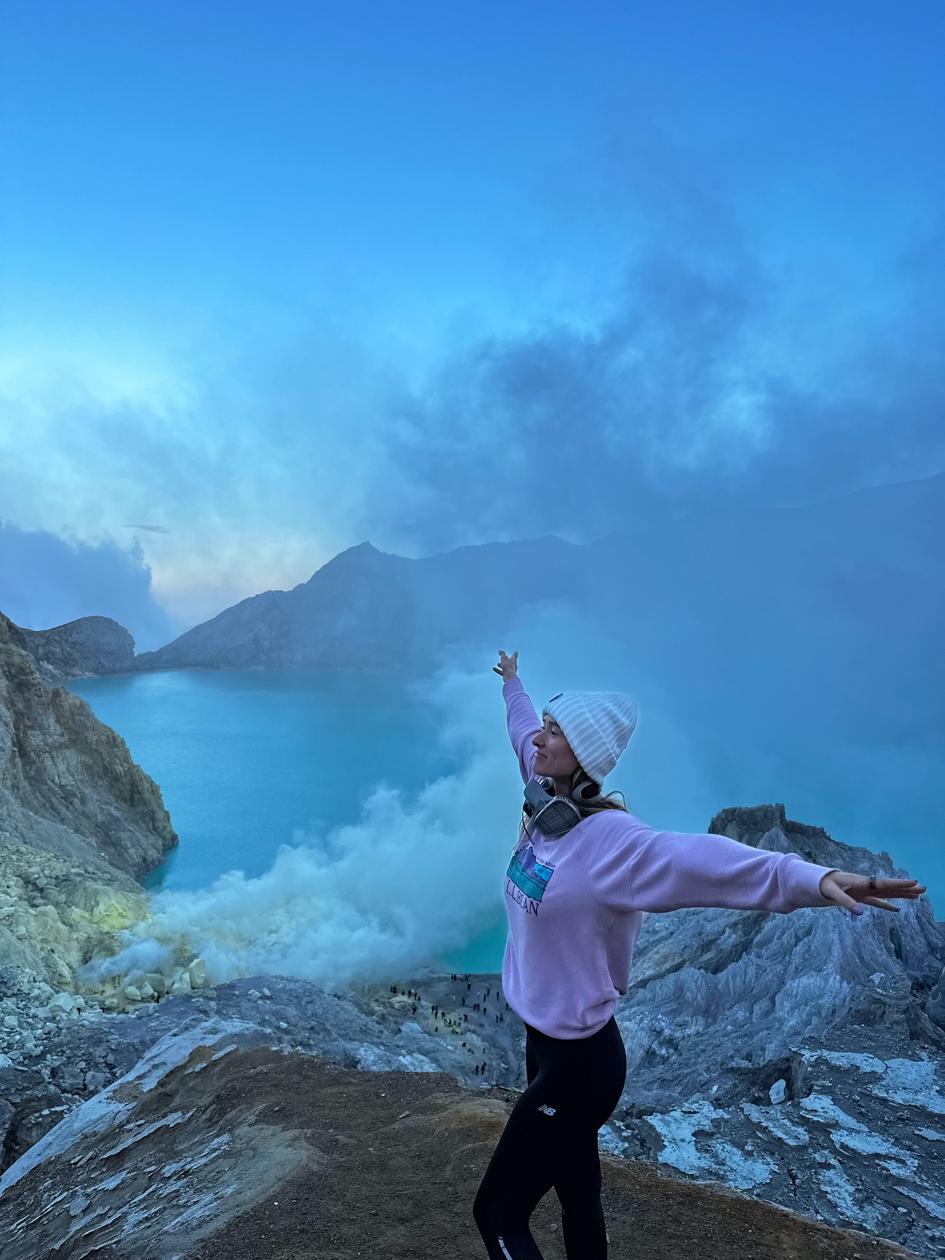 Traveler posing above the turquoise crater lake at Kawah Ijen volcano
