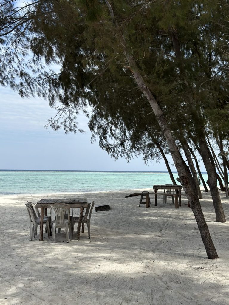 Quiet white-sand beach with shaded tables and turquoise water on Gili Rengit, Lombok