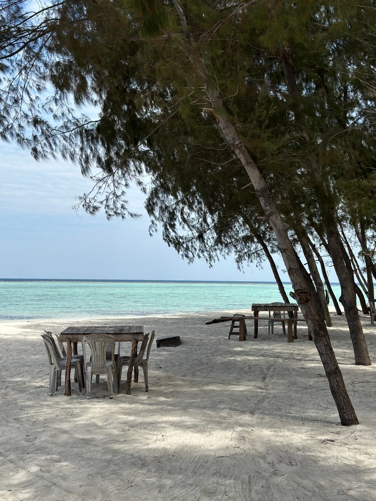 Quiet white sand beach with shaded tables and turquoise water on Gili Renggit, Lombok