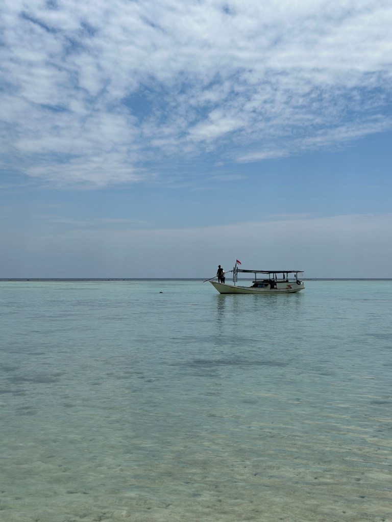 Small boat floating on calm clear water during an island hopping trip around Gili Gede, Gili Layar and Gili Renggit