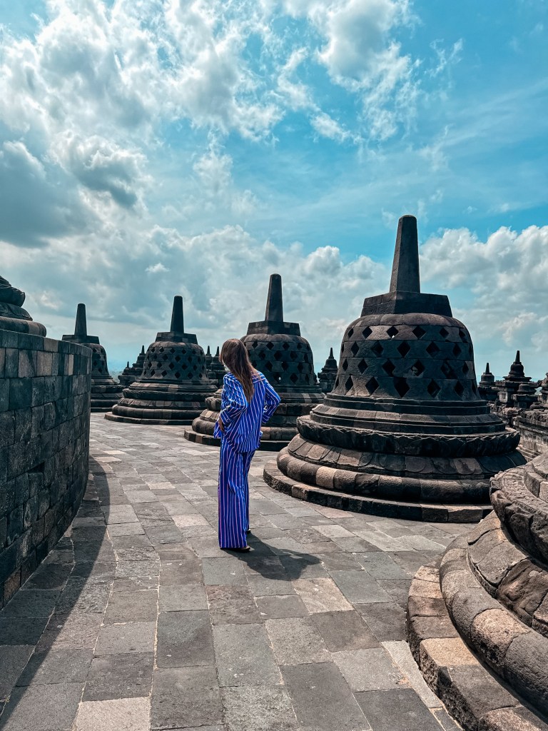 Woman walking among the bell-shaped stupas at Borobudur Temple
