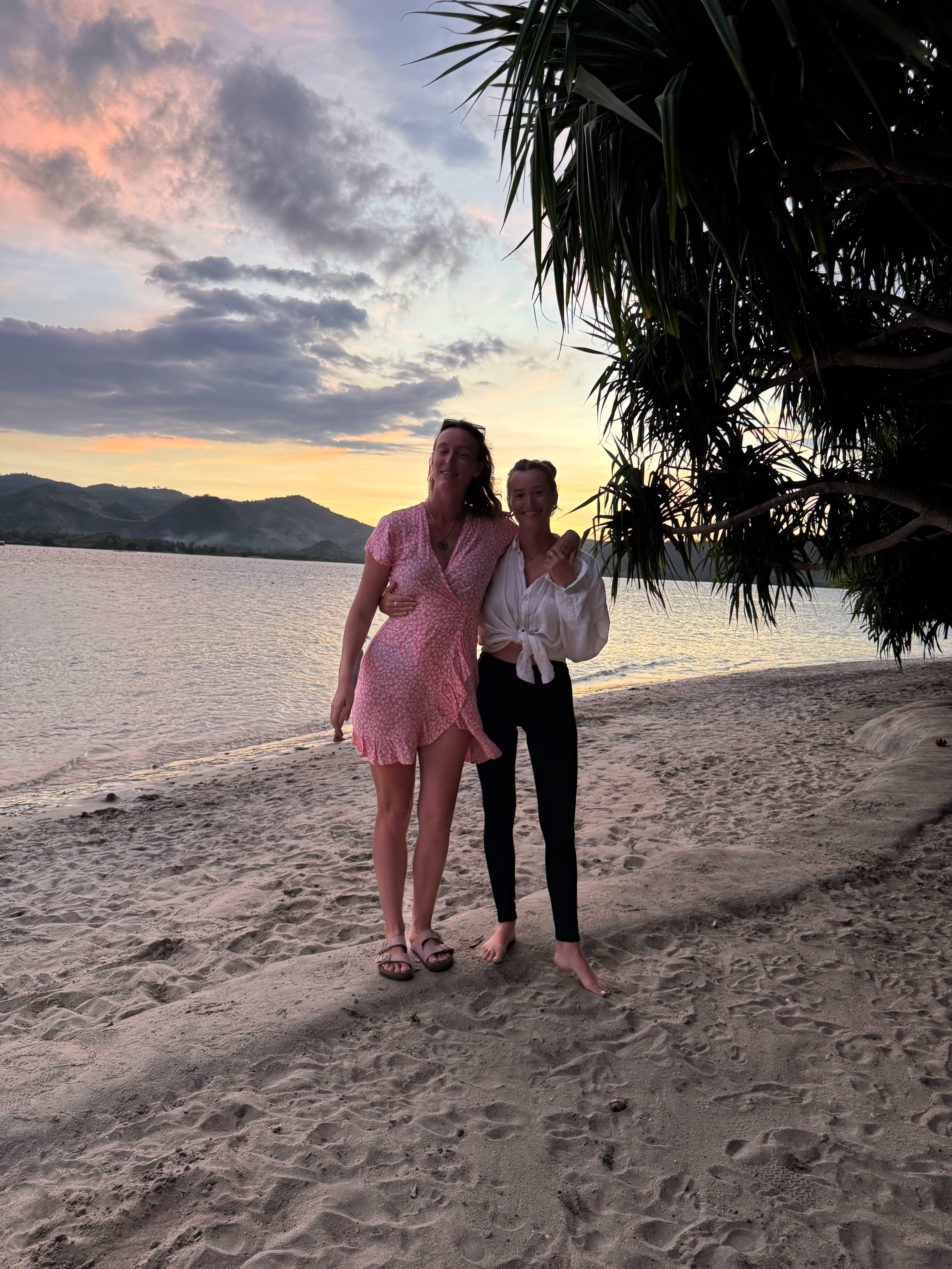 Two people walking on a quiet Gili Asahan beach at sunset