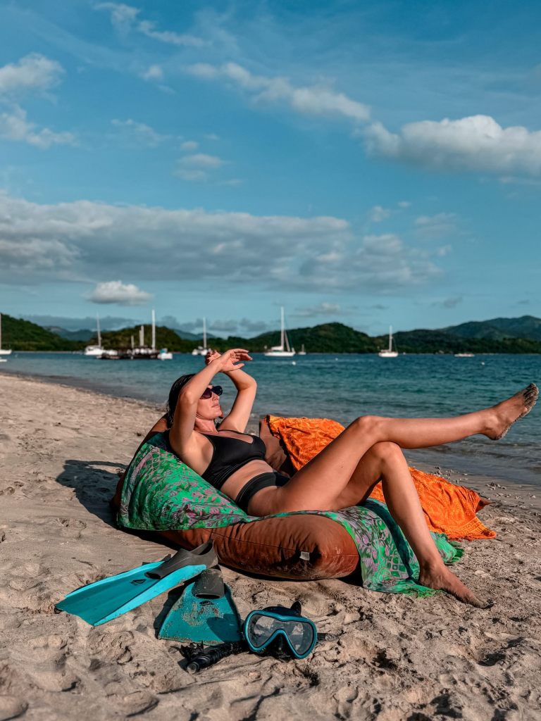 Carlijn relaxing on a Lombok beach with boats in the background for her Lombok travel guide