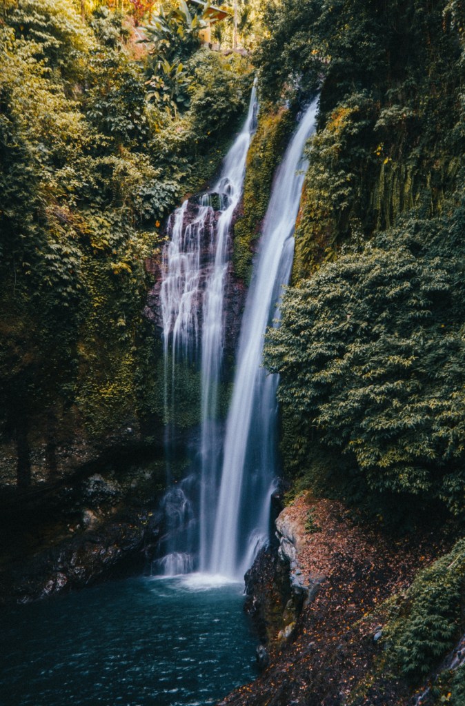 Tall jungle waterfall surrounded by lush forest in Munduk, Bali