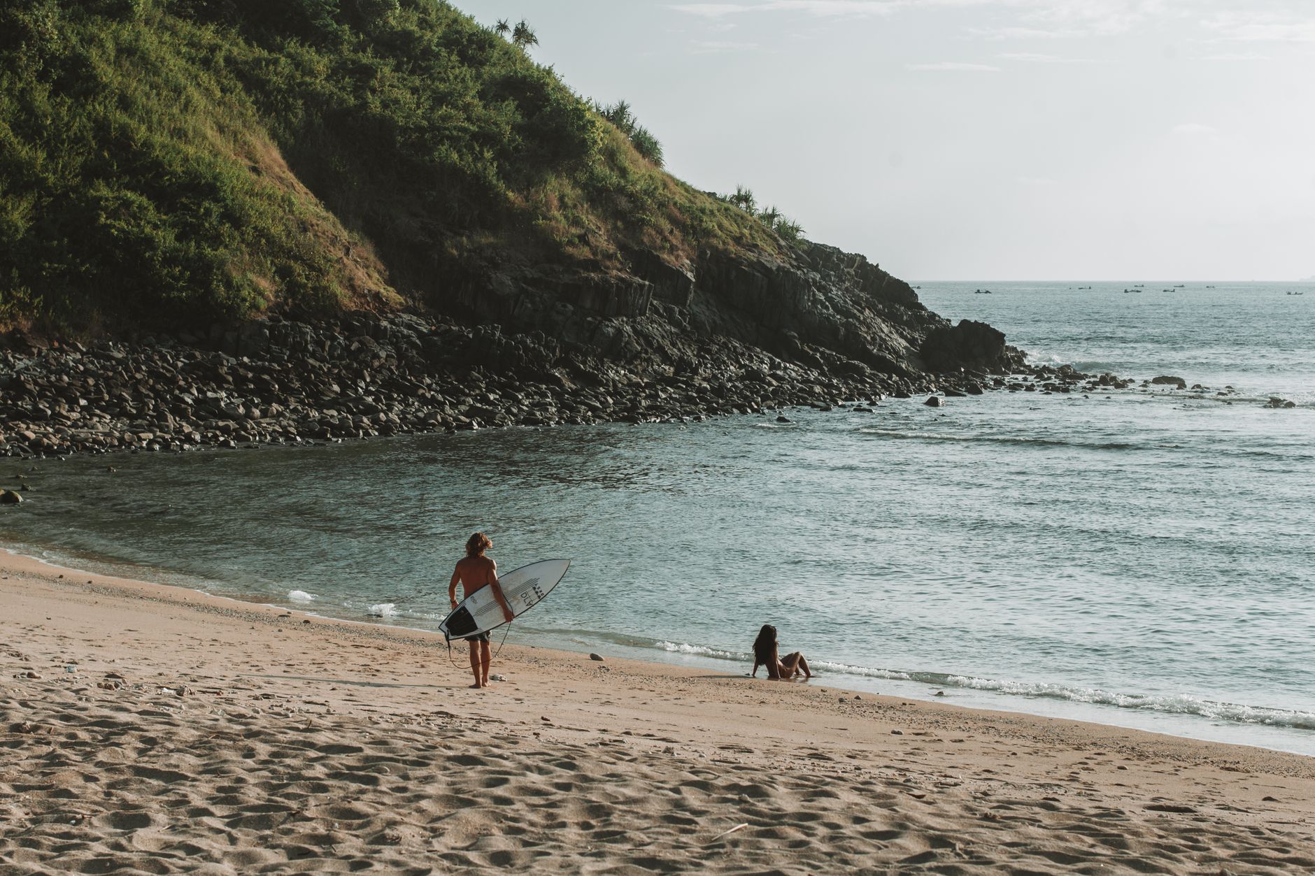 Surfer walking toward the ocean on a sandy beach in South Lombok, Indonesia