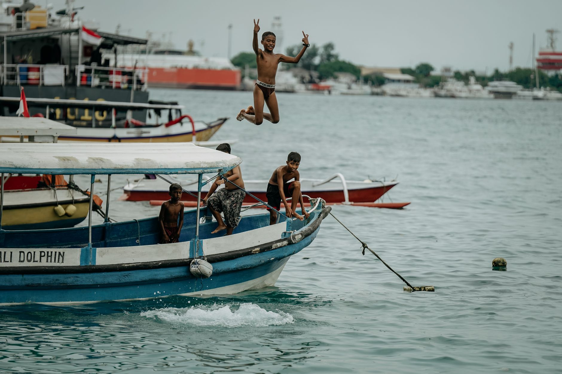 Local boy jumping from a boat during a dolphin watching trip in Lovina, North Bali