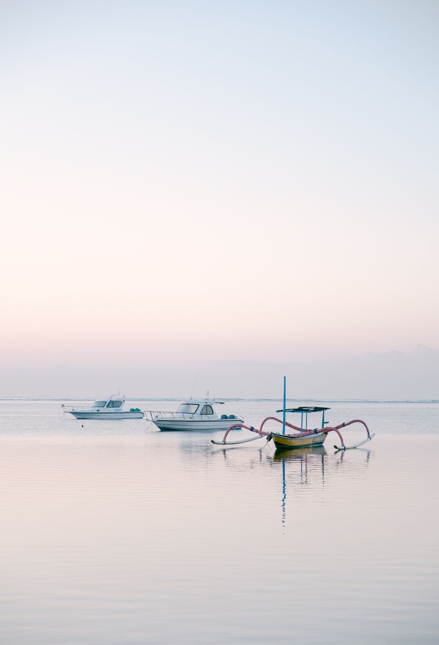 Traditional fishing boats floating on calm water at sunrise in Lovina, North Bali