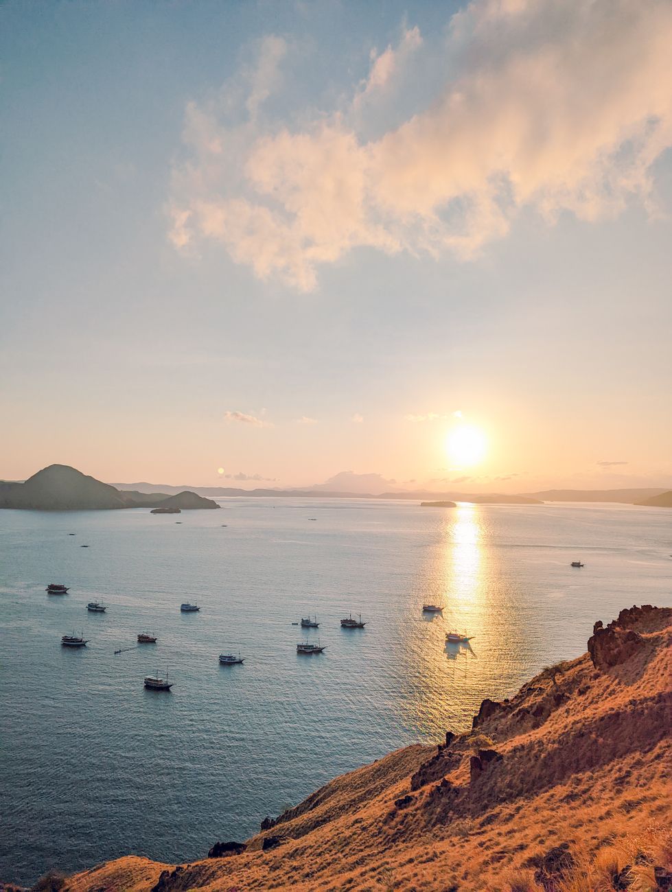 Sunset over the sea and anchored liveaboards viewed from the hills of Padar Island.