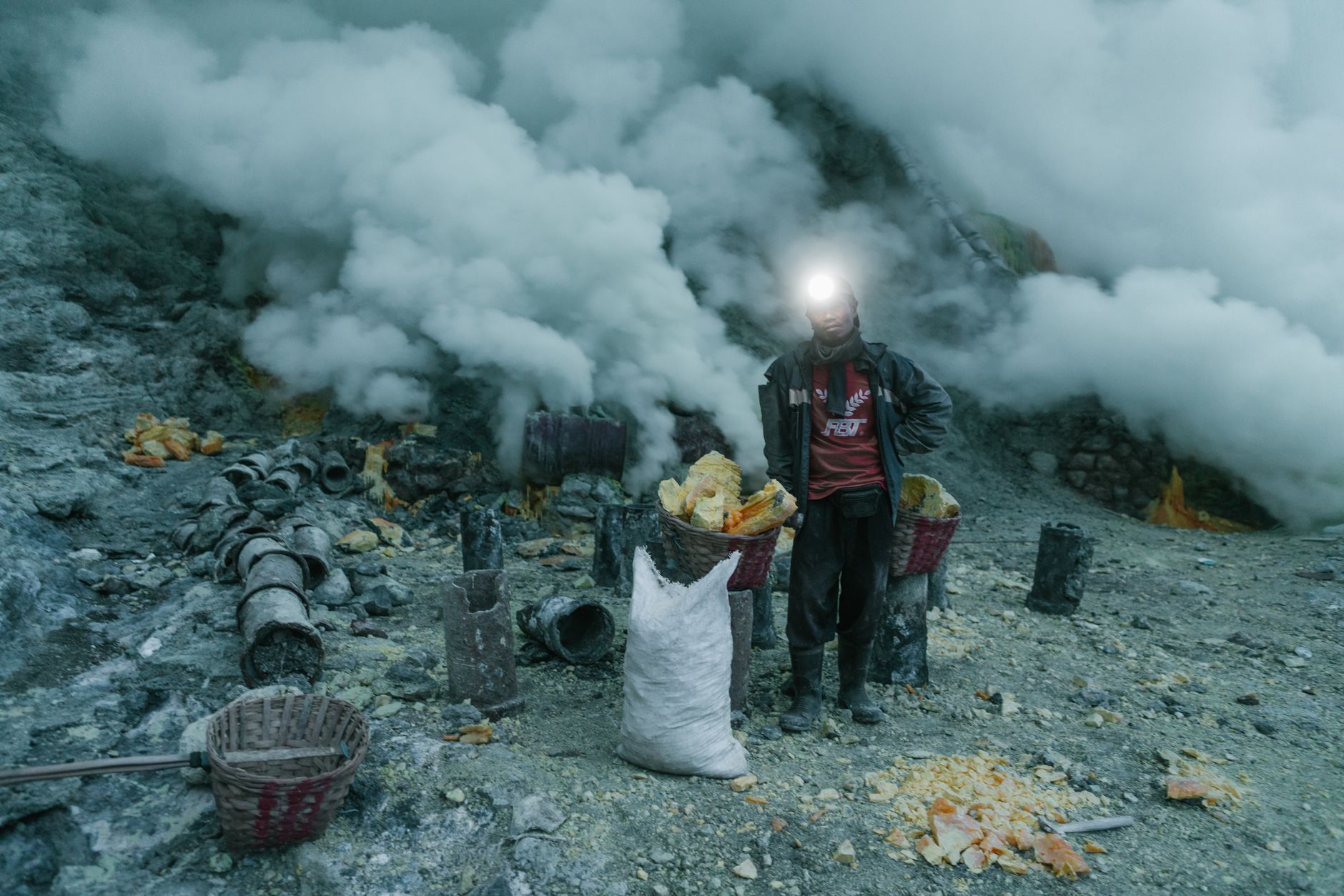 Sulfur miner carrying baskets near the smoking crater of Mount Ijen