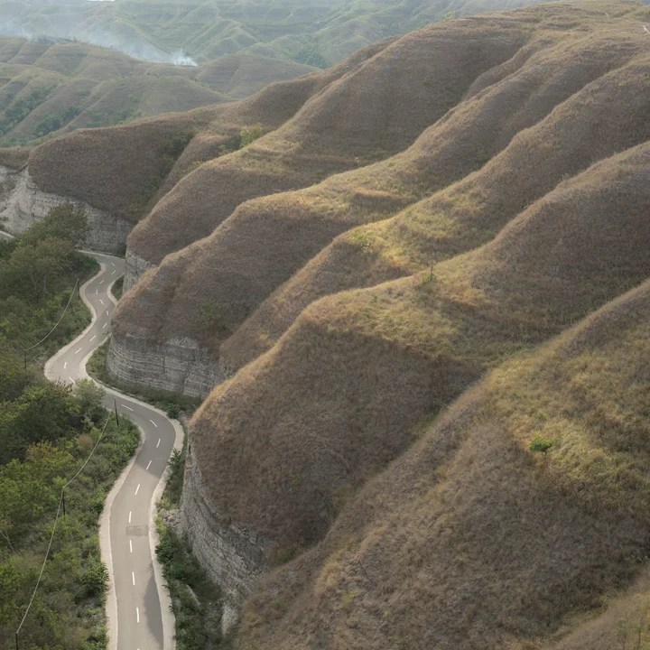 Winding road through green hills at Palindi Piarakuku Hills in East Sumba