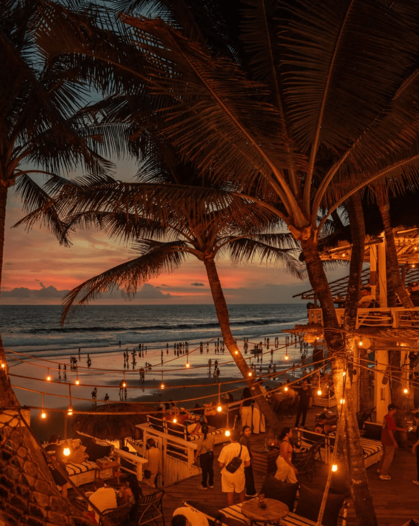 Sunset beach club scene with palm trees and ocean views in Canggu