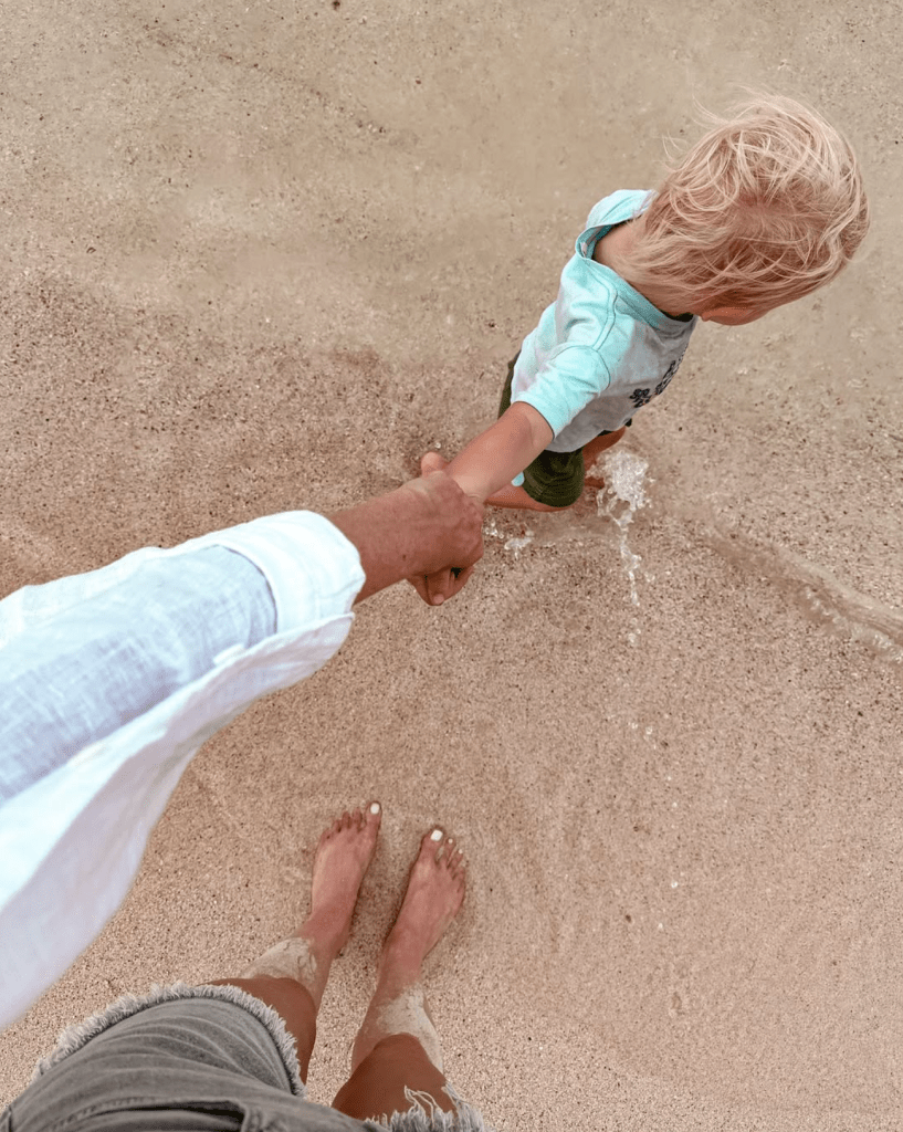 Noah walking along the beach while holding hands during a family travel moment