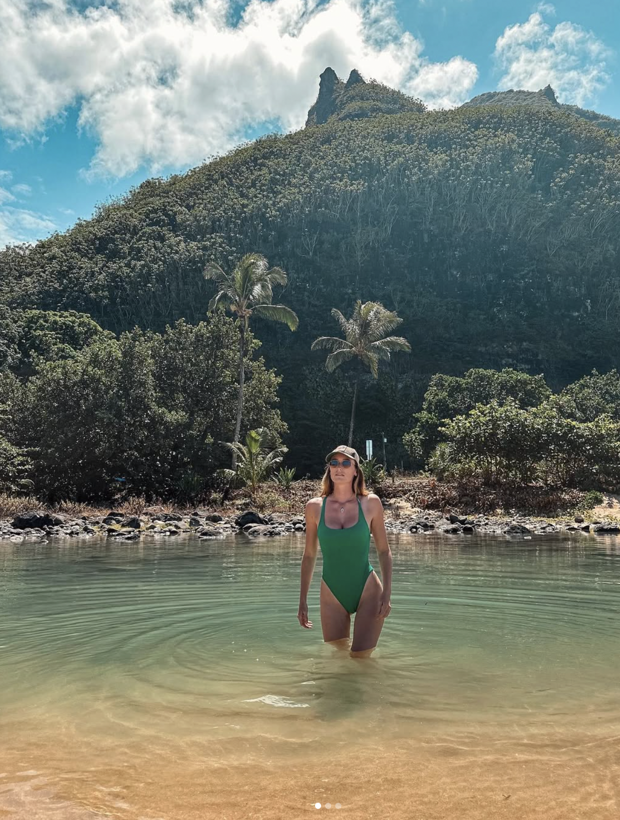 Carlijn swimming in clear water with green mountains behind her in Kauai, Hawaii