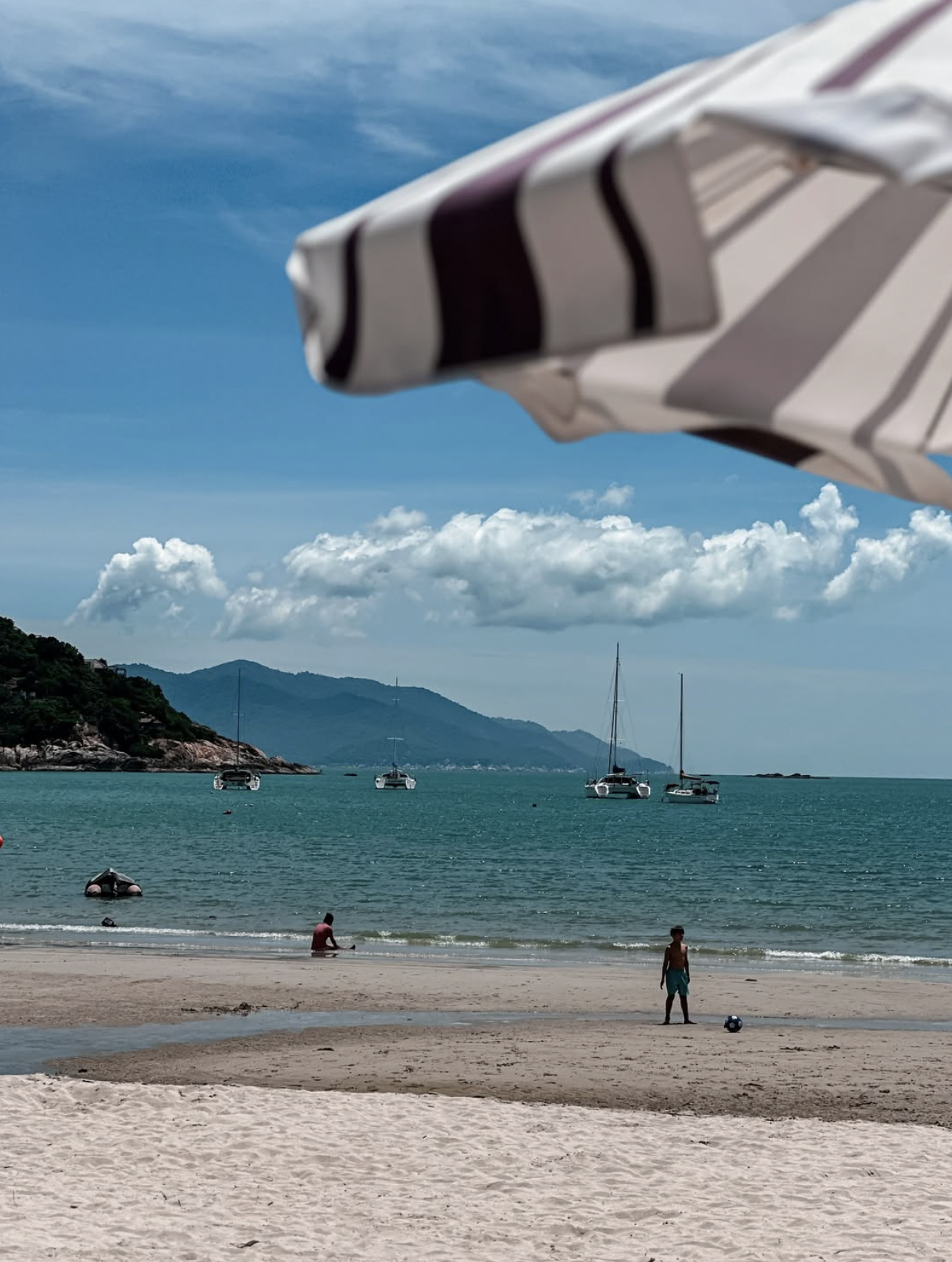 Quiet beach in Koh Samui with boats and mountain views in Thailand
