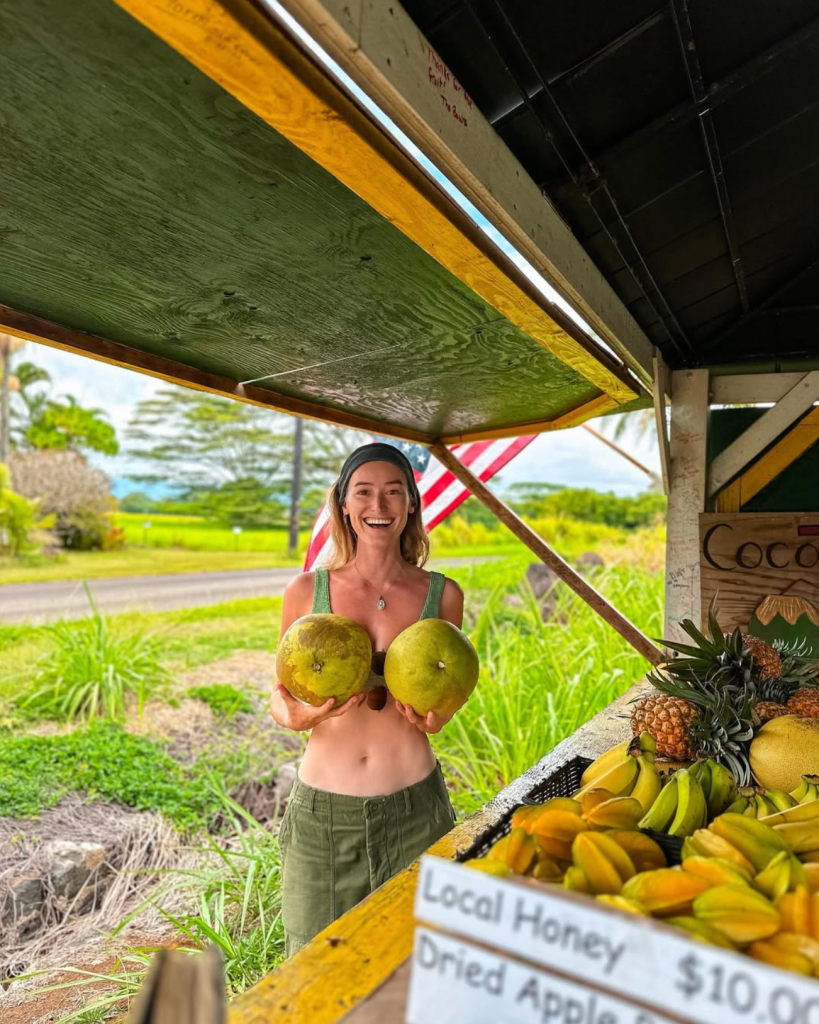 Carlijn de Jong holding fresh coconuts at a tropical fruit stand during a travel day in Kauaii, Hawaii