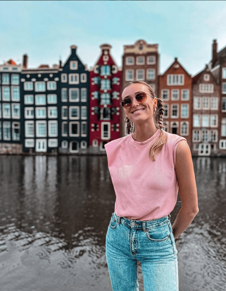 Carlijn smiling in front of colorful canal houses in Amsterdam, Netherlands