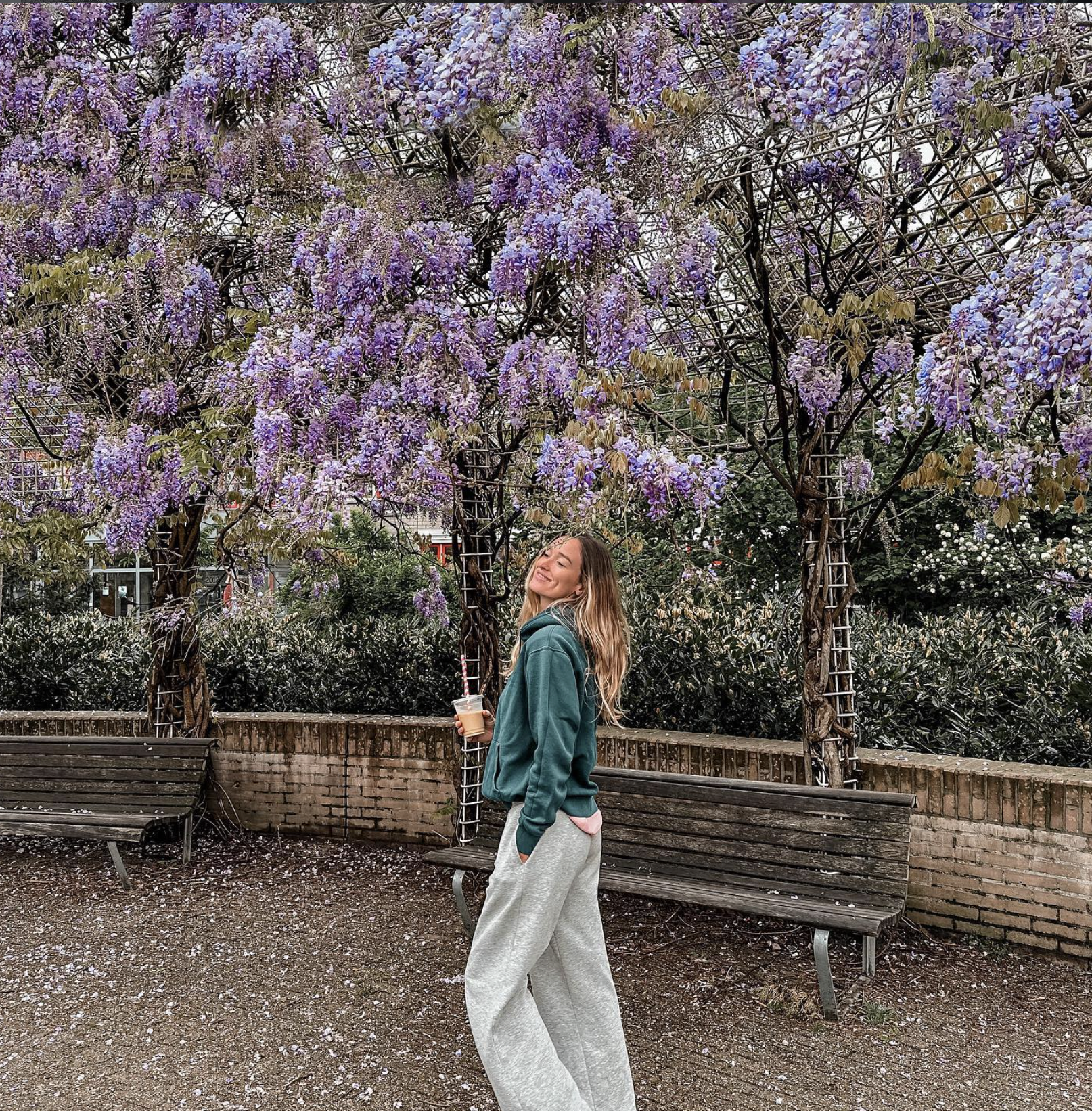 Carlijn standing under purple wisteria flowers in Amsterdam