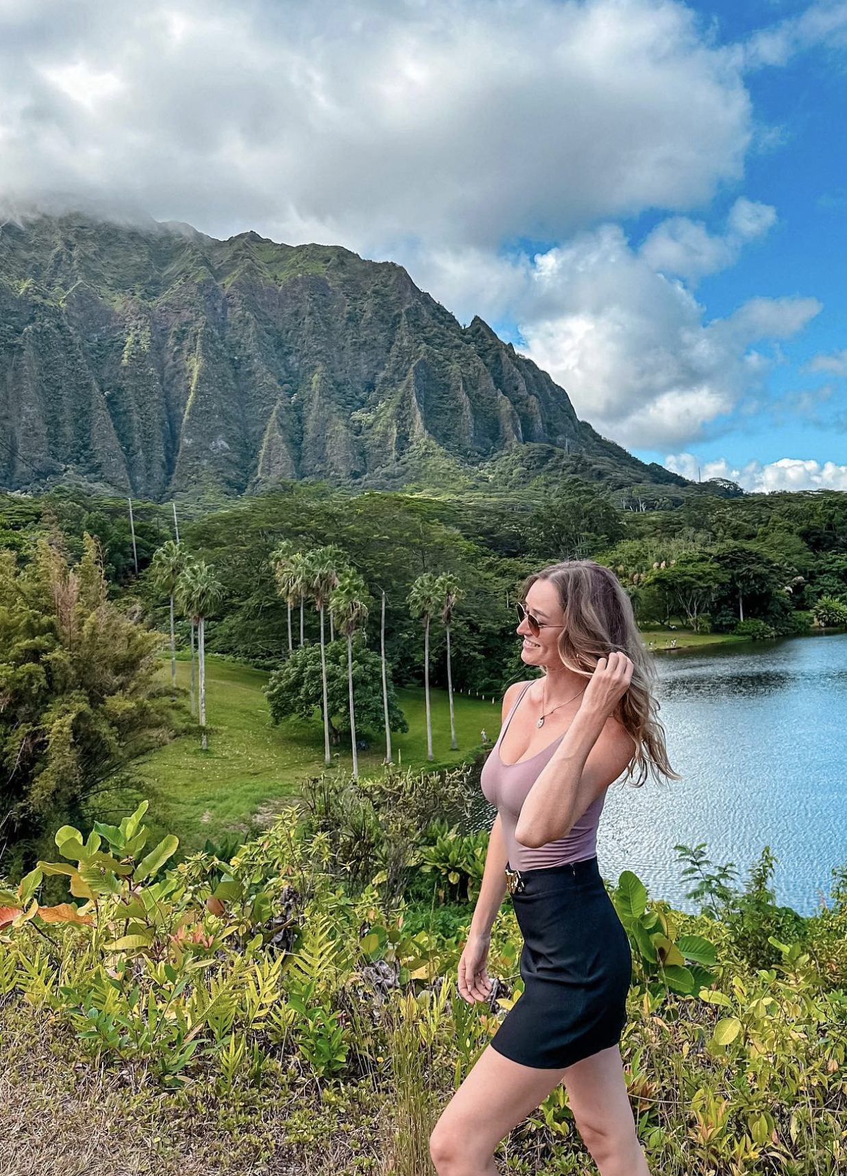 Carlijn walking by lush mountains and a lake in Oahu, Hawaii