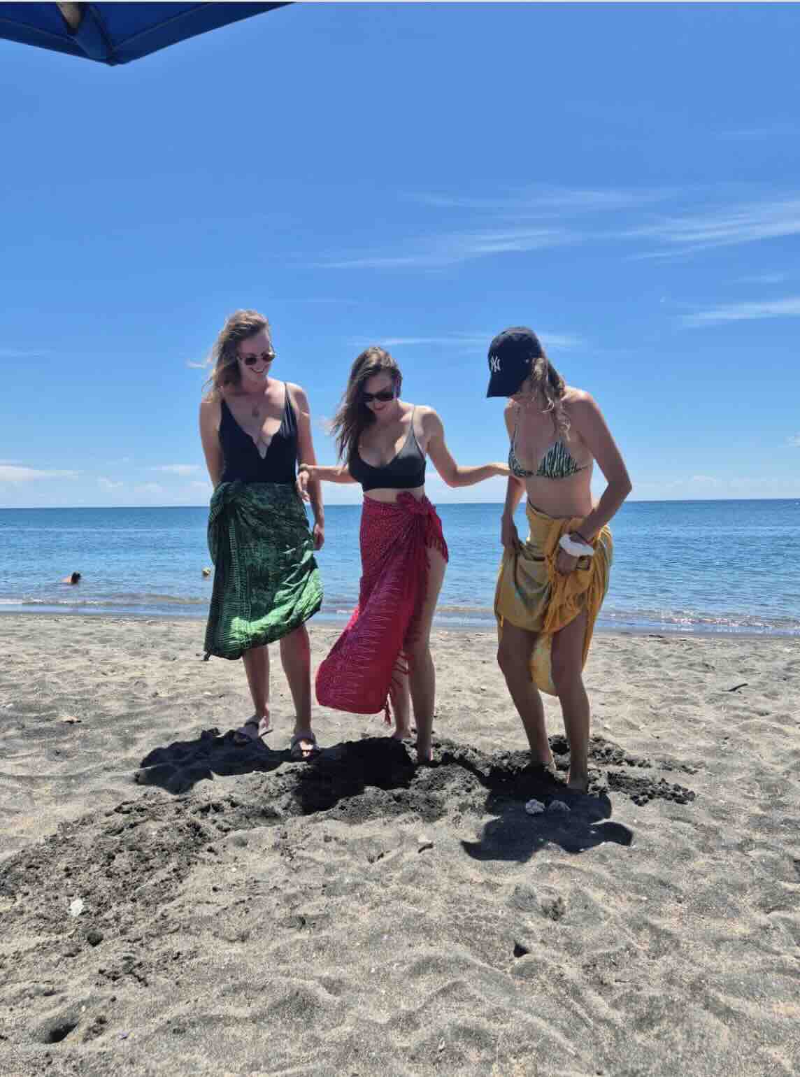 Travelers walking on a black sand beach in Amed, Bali