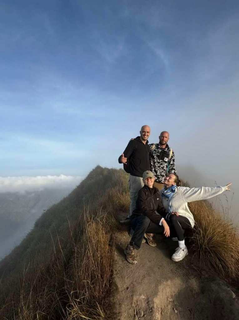 Travelers standing on the summit of Mount Batur during a sunrise hike in Bali