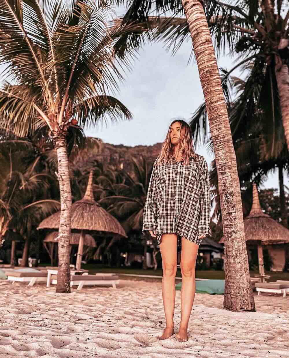 Woman standing beneath palm trees on a tropical beach in Mauritius.