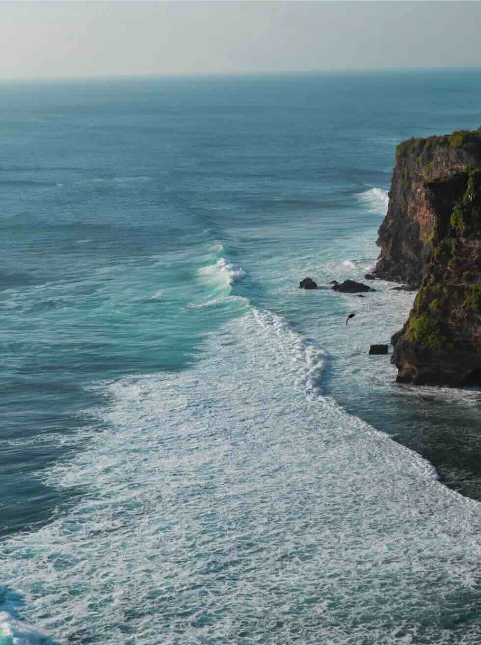 Dramatic limestone cliffs and ocean waves along the Uluwatu coastline in Bali