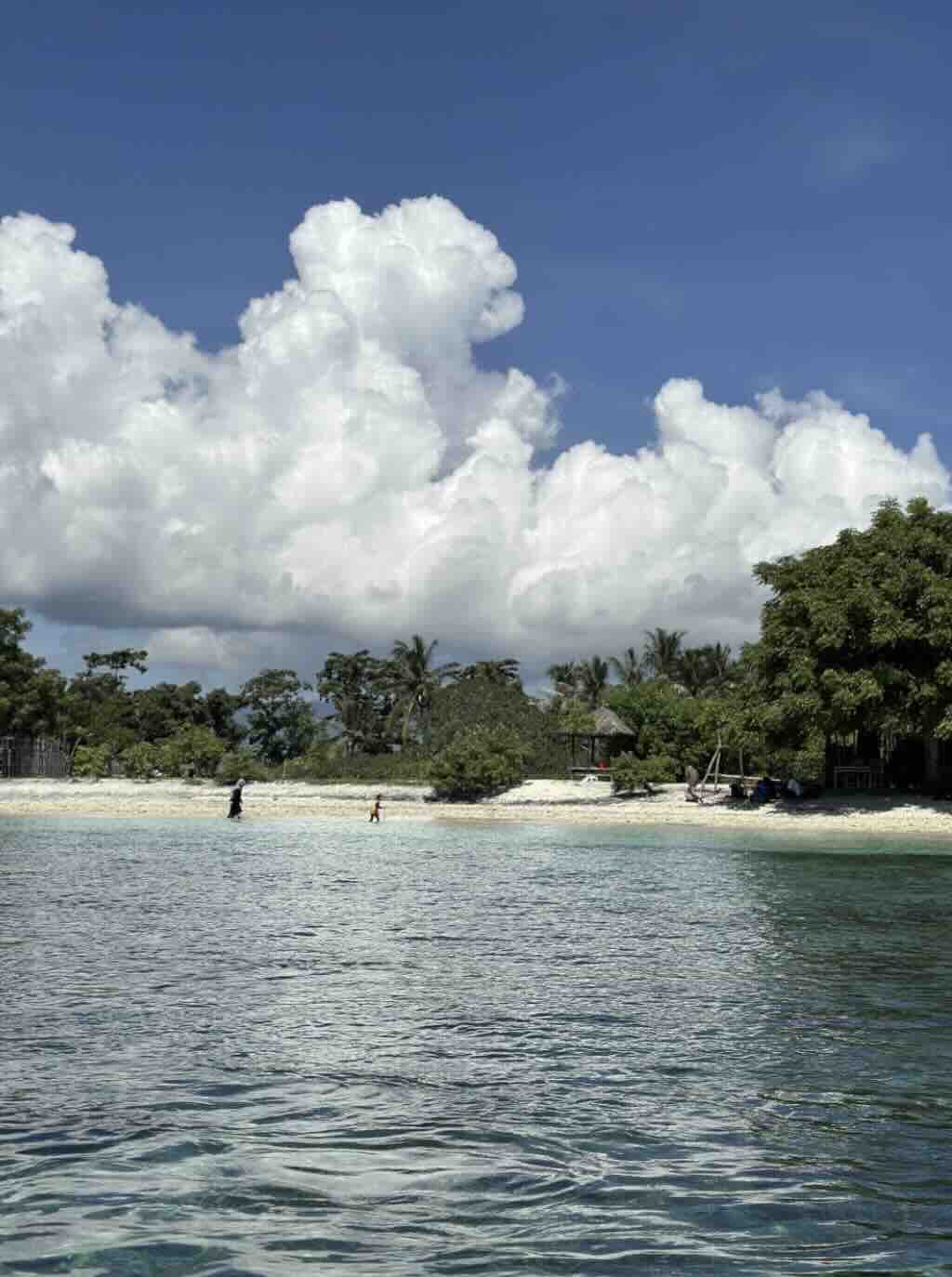 Peaceful beach on Gili Asahan with clear water, white sand and dramatic clouds