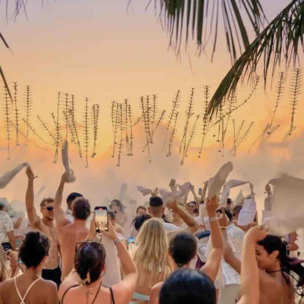 Crowd enjoying a beach club party at sunset in Uluwatu, Bali