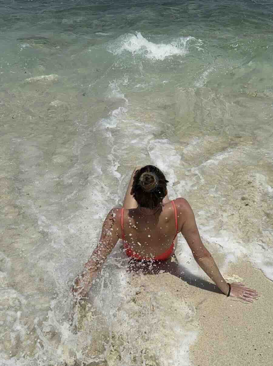 Traveler sitting in the waves on a sandy beach in Nusa Lembongan, Bali