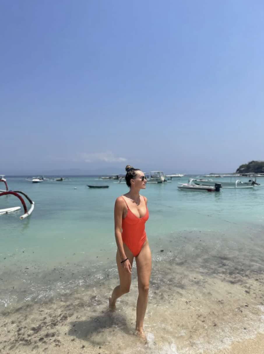 Traveler standing in clear shallow water on a beach in Nusa Lembongan, Bali