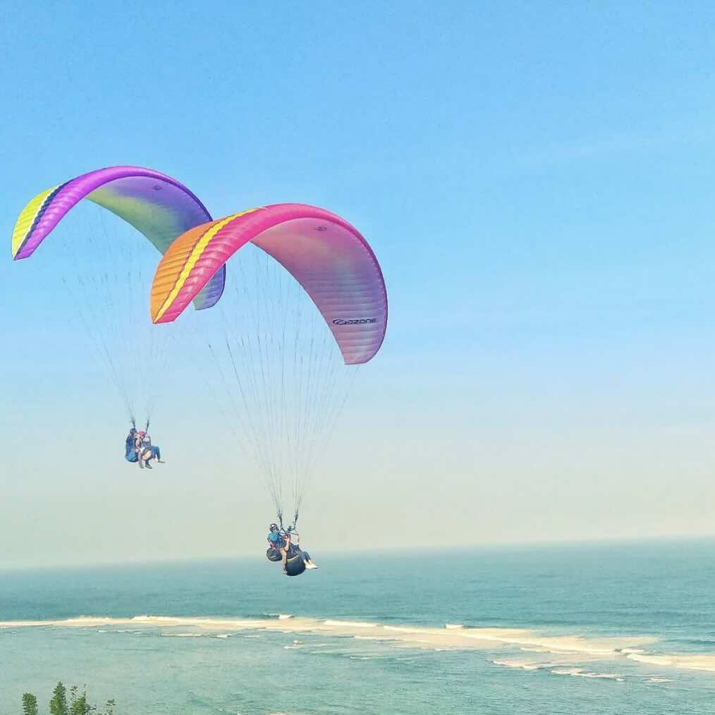 Paragliders flying above the ocean and cliffs in Uluwatu, Bali