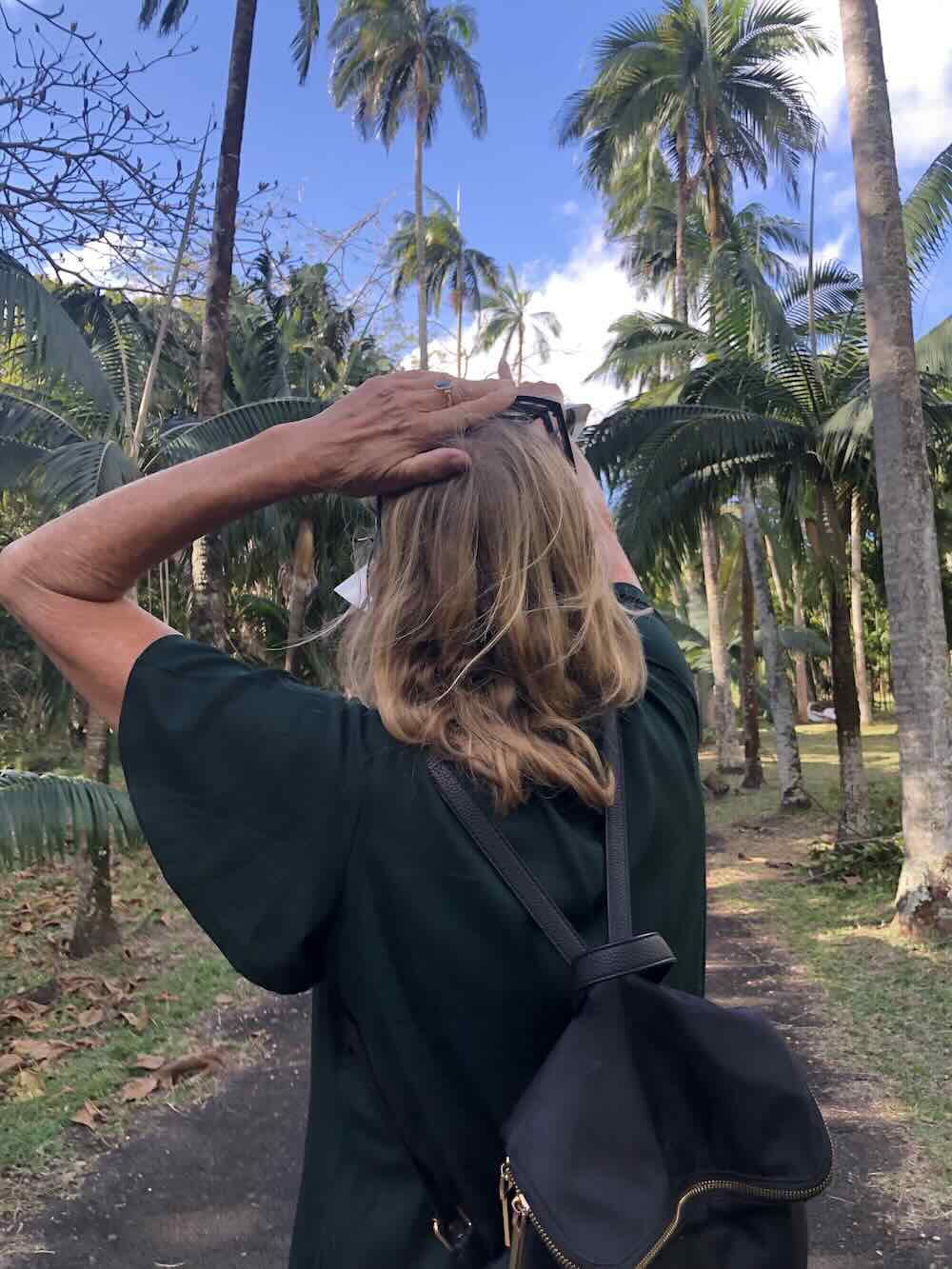Woman walking beneath towering palm trees at Sir Seewoosagur Ramgoolam Botanical Garden in Mauritius.