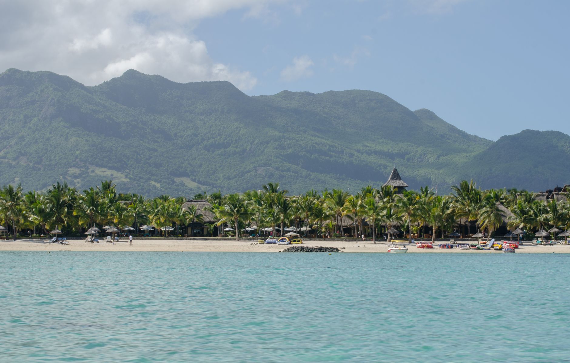 Palm-lined beach at Île aux Cerfs with mountains in the background in Mauritius.