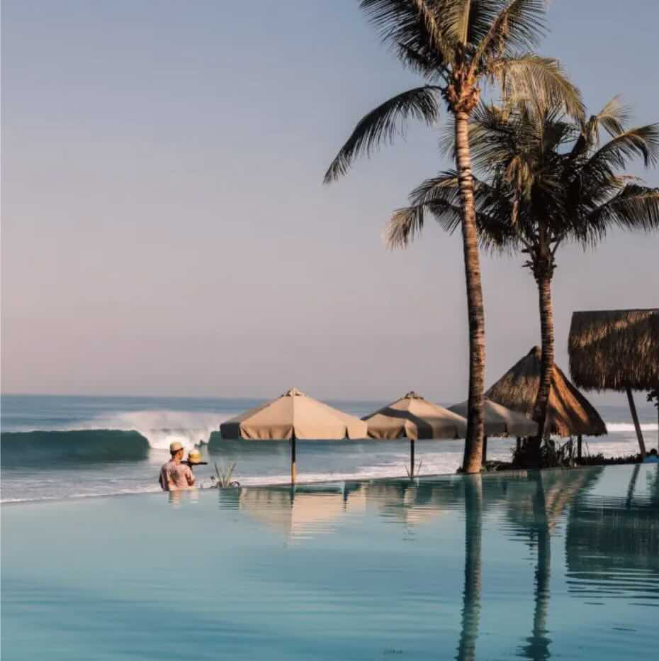 Beach club pool with palm trees and ocean views in Seminyak, Bali